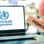 Laptop mit Logo der Weltgesundheitsorganisation und Handstempel mit dem Wort „abgelehnt“